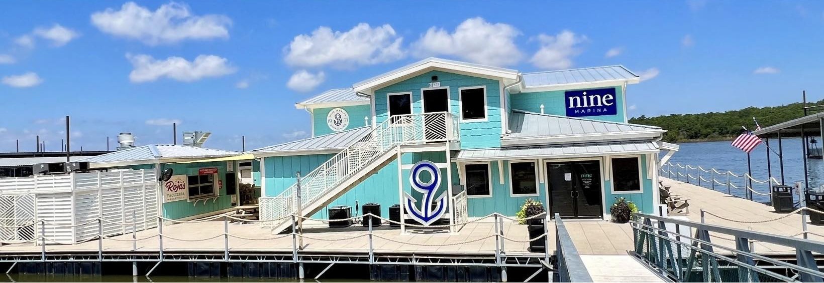 The Nine Marina building on Lake Eufaula — aquamarine cantina, 9-anchor on the wall, Roja's Taqueria, lake and sky.